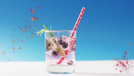 Animation-of-confetti-falling-and-cocktail-on-blue-background