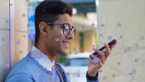 Animation-of-connected-icons-over-biracial-man-smiling-and-talking-on-speaker-of-smartphone