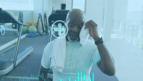 Animation-of-graphs-and-icons-over-tired-african-american-man-wiping-head-with-towel-in-gym