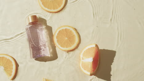 Video-Einer-Kosmetikflasche-Und-Orangenscheiben-Im-Wasser-Mit-Kopierraum-Auf-Gelbem-Hintergrund