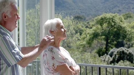 Happy-senior-caucasian-couple-standing-on-balcony-and-embracing,-slow-motion