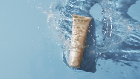 Video-of-beauty-product-tube-in-water-with-copy-space-on-blue-background