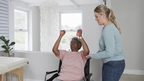 Caucasian-female-physiotherapist,senior-african-american-woman-in-wheelchair-exercising,-slow-motion