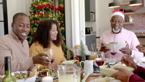 Glückliche-Afroamerikanische-Mehrgenerationenfamilie,-Die-Am-Weihnachtstisch-Gerichte-Serviert