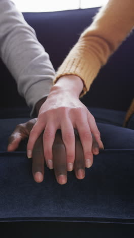 Hands-of-diverse-couple-sitting-on-sofa-in-house,-slow-motion