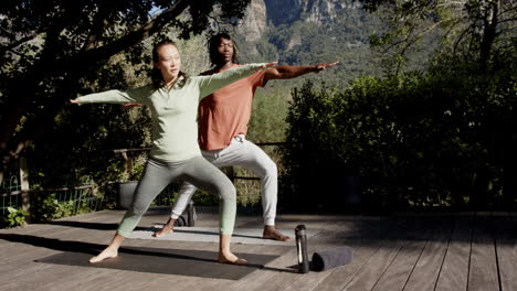 Happy-diverse-couple-practicing-yoga-standing-in-sunny-garden,-copy-space,-slow-motion