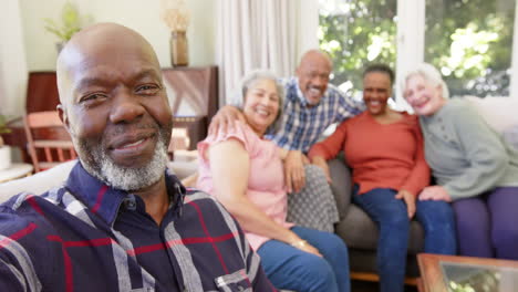 Glücklicher-älterer-Afroamerikanischer-Mann,-Der-Selfie-Mit-Verschiedenen-Freunden-In-Sonnigem-Zimmer-Macht,-Zeitlupe
