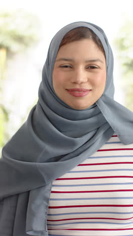 Vertical-video-of-portrait-happy-biracial-woman-in-hijab,-copy-space,-slow-motion