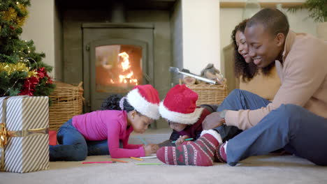Glückliche-Afroamerikanische-Eltern,-Sohn-Und-Tochter-Zeichnen-Zu-Weihnachten-Im-Wohnzimmer,-Zeitlupe