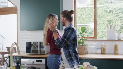 Happy-diverse-couple-dancing-in-kitchen-at-home,-in-slow-motion