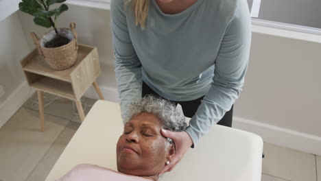 Caucasian-female-physiotherapist-massaging-head-of-senior-woman,-copy-space,-slow-motion