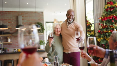 Glückliches,-Vielfältiges-Seniorenpaar-Und-Freunde-Stoßen-Beim-Weihnachtsessen-Mit-Wein-An,-Zeitlupe