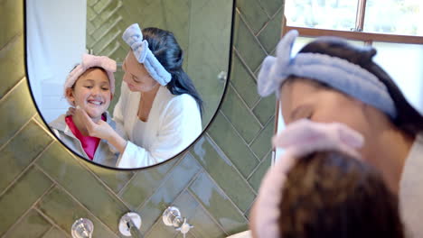 Glückliche-Biracial-Mutter-Und-Tochter-Mit-Stirnbändern-Kümmern-Sich-Um-Gesichter-In-Sonnigen-Badezimmer