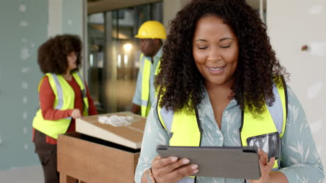 Smiling-casual-biracial-female-architect-with-tablet-in-office,-slow-motion,-copy-space