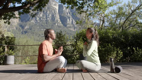 Happy-diverse-couple-practicing-yoga-meditation-sitting-in-sunny-nature,-copy-space,-slow-motion