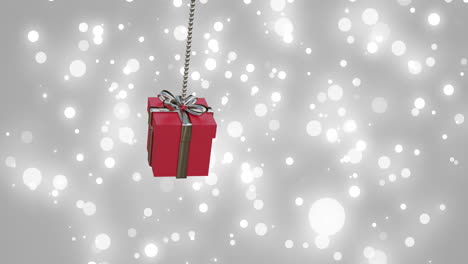 Animation-of-red-christmas-gift-bauble-and-snow-falling-on-grey-background