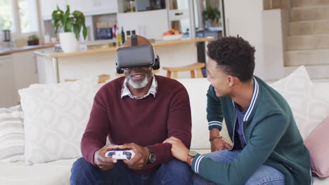 Glücklicher-Afroamerikanischer-Vater-Mit-VR-Headset-Und-Gamepad-Mit-Erwachsenem-Sohn-Zu-Hause,-Zeitlupe