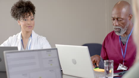 Diverse-doctors-using-laptops-in-meeting-room-with-copy-space,-slow-motion