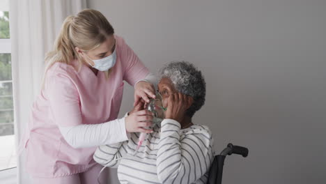 Caucasian-female-nurse-in-face-mask,-senior-african-american-woman-with-oxygen-mask,-slow-motion