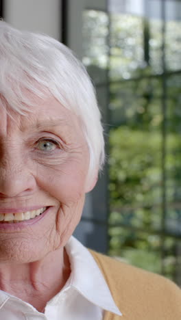 Vertical-video-of-portrait-of-happy-senior-caucasian-woman-smiling-at-home,-slow-motion