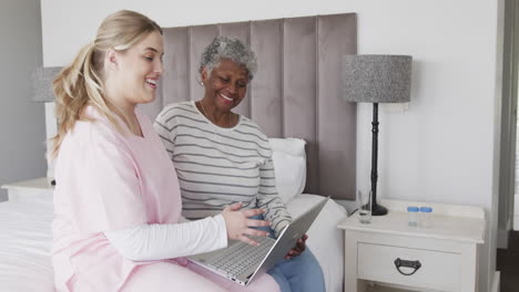 Caucasian-female-nurse-and-senior-african-american-woman-using-laptop,-copy-space,-slow-motion