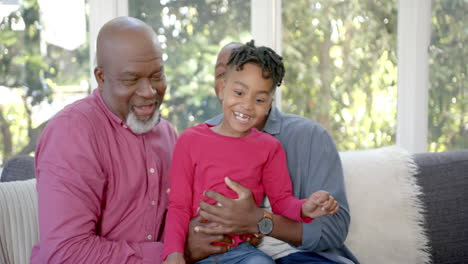 Portrait-of-happy-african-american-father,-son-and-grandfather-on-couch-in-sunny-room,-slow-motion