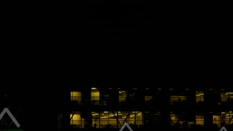 Animation-Mehrerer-Aufwärtspfeile-über-Der-Luftaufnahme-Eines-Beleuchteten-Modernen-Gebäudes-Vor-Dem-Nachthimmel