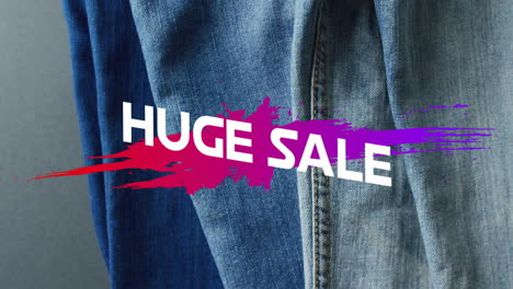 Animation-of-huge-sale-text-over-denim-trousers-background