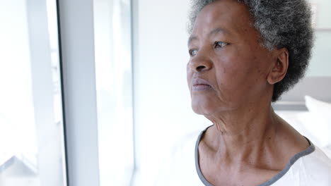 Paciente-Senior-Afroamericana-Mirando-Por-La-Ventana-En-La-Habitación-Del-Hospital,-Cámara-Lenta
