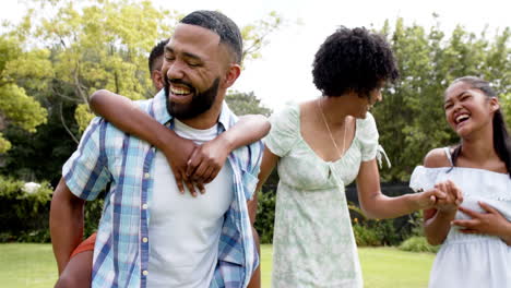 Glückliche-Afroamerikanische-Eltern,-Tochter-Und-Sohn-Huckepack-Und-Spazieren-Im-Garten,-Zeitlupe