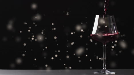 Composite-of-glass-of-red-wine-over-spots-of-light-on-black-background