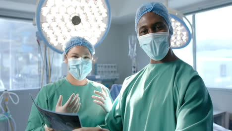Porträt-Verschiedener-Chirurginnen-Und-Chirurgen-In-Masken-Mit-Röntgenstrahlen-Im-Operationssaal,-Zeitlupe