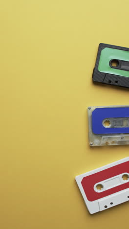 Vertical-video-of-retro-tapes-with-copy-space-on-yellow-background