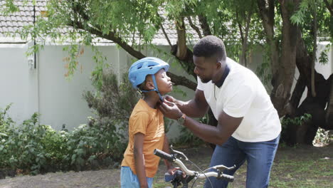 African-American-father-helps-son-with-bike-helmet-outdoors