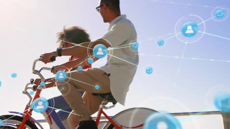 Animation-of-network-of-connections-with-icons-over-diverse-couple-on-bikes-by-sea