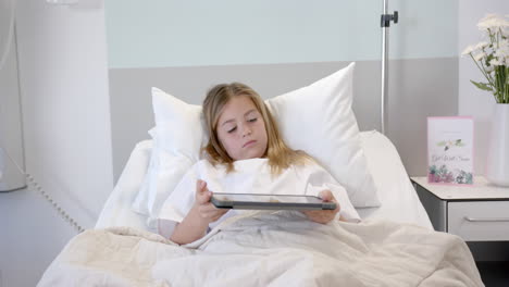 Tired-caucasian-girl-patient-lying-in-hospital-bed-using-tablet,-slow-motion