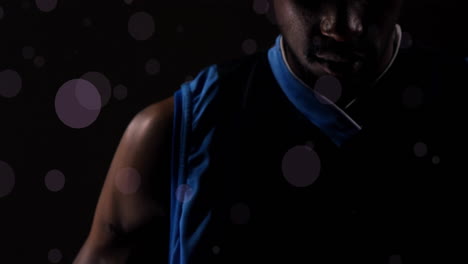 Animation-of-african-ameerican-basketball-player-with-ball-and-spots-of-light-on-black-background
