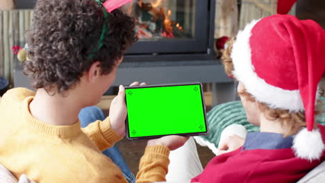 Two-caucasian-male-friends-having-christmas-tablet-video-call-with-green-screen,-slow-motion