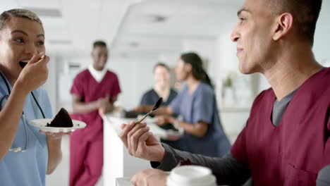 Diverse-male-and-female-doctors-eating-birthday-cake-at-reception-desk-at-hospital,-slow-motion