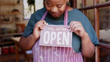 Happy-african-american-female-business-owner-holding-shop-sign-to-open-and-smiling,-slow-motion