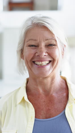 Happy-caucasian-senior-woman-standing-and-laughing-in-sunny-room,-slow-motion