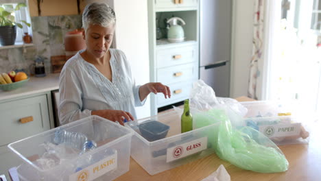 Focused-senior-biracial-woman-segregating-waste-at-home,-slow-motion