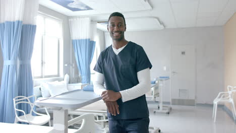 Portrait-of-happy-african-american-male-doctor-standing-in-hospital-ward,-copy-space,-slow-motion