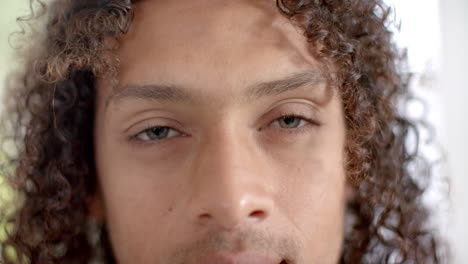 Portrait-close-up-of-happy-biracial-man-with-long-curly-hair-smiling,-slow-motion