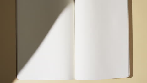 Video-Von-Schatten-über-Einem-Buch-Mit-Leeren-Weißen-Seiten-Und-Kopierraum-Auf-Gelbem-Hintergrund