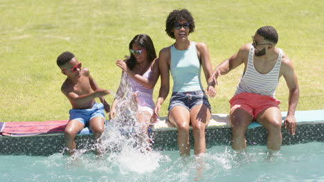 Happy-african-american-parents,-son-and-daughter-sitting-in-sun-splashing,-feet-in-pool,-slow-motion