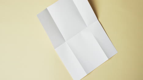 Video-Eines-Weißen-Blattes-Papier-Mit-Falten-Auf-Gelbem-Hintergrund