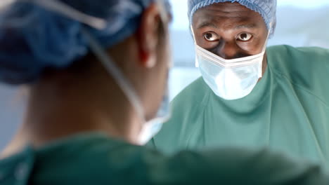 Diverse-female-and-male-surgeons-in-masks-talking-during-operation-in-theatre,-slow-motion