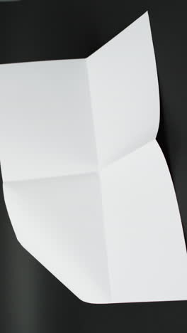 Vertical-video-of-piece-of-white-paper-with-creases-on-black-background