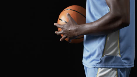 Afroamerikanischer-Mann-Hält-Einen-Basketball-Auf-Schwarzem-Hintergrund